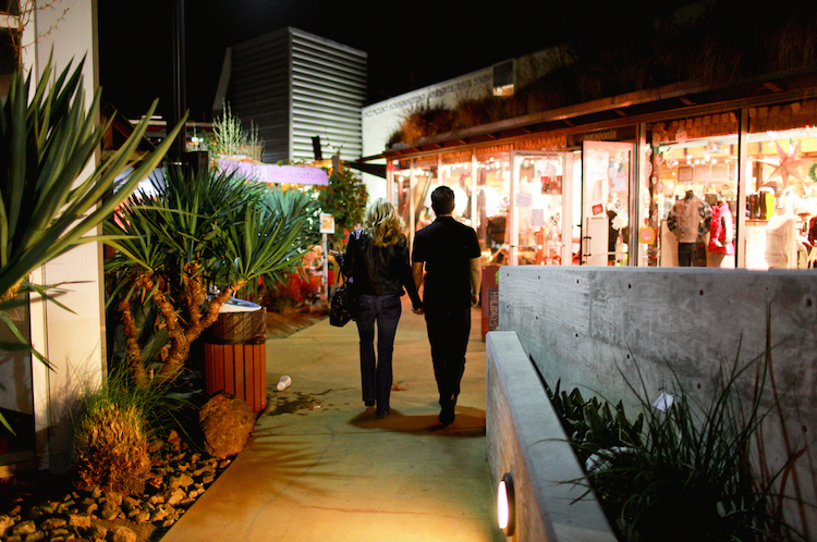 A couple holding hands shopping at The CAMP at night in Costa Mesa.