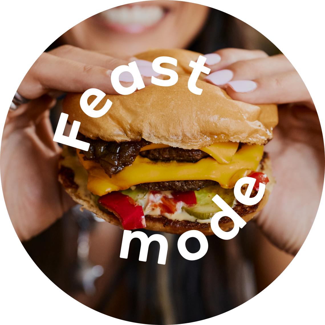 A person in Costa Mesa holding a large cheeseburger with toppings, smiling in the background. The words “Feast mode” are overlaid on the image in bold white text.