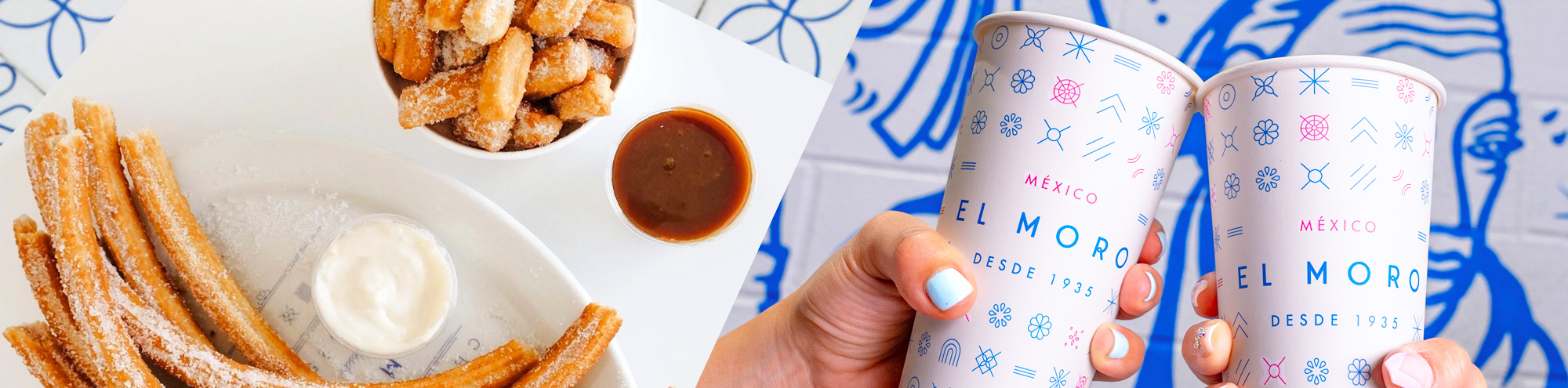 A plate of churros with two dipping sauces and a cup of churros bites sits by hands holding white El Moro cups, all set against a blue-and-white illustrated wall at Churrería El Moro Costa Mesa.