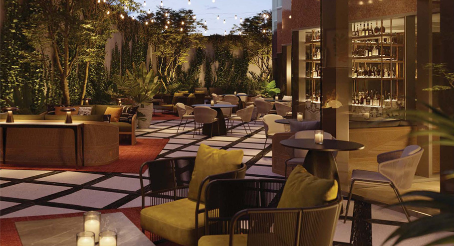 Outdoor lounge area with modern furniture, cushioned chairs, candlelit tables, string lights, lush greenery, and a well-stocked bar—one of the most inviting meeting venues Costa Mesa offers for a cozy and elegant atmosphere at dusk.