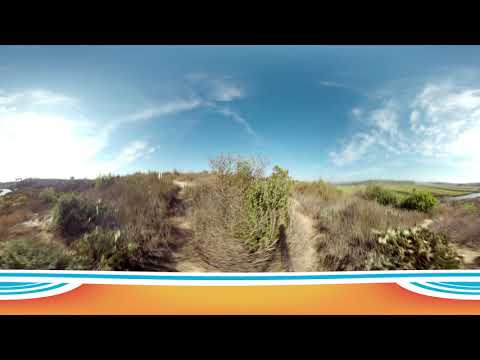 A panoramic view of Upper Newport Bay Nature Reserve’s coastal landscape with dry bushes and grass under a blue sky, featuring a decorative orange and blue border at the bottom of the image.