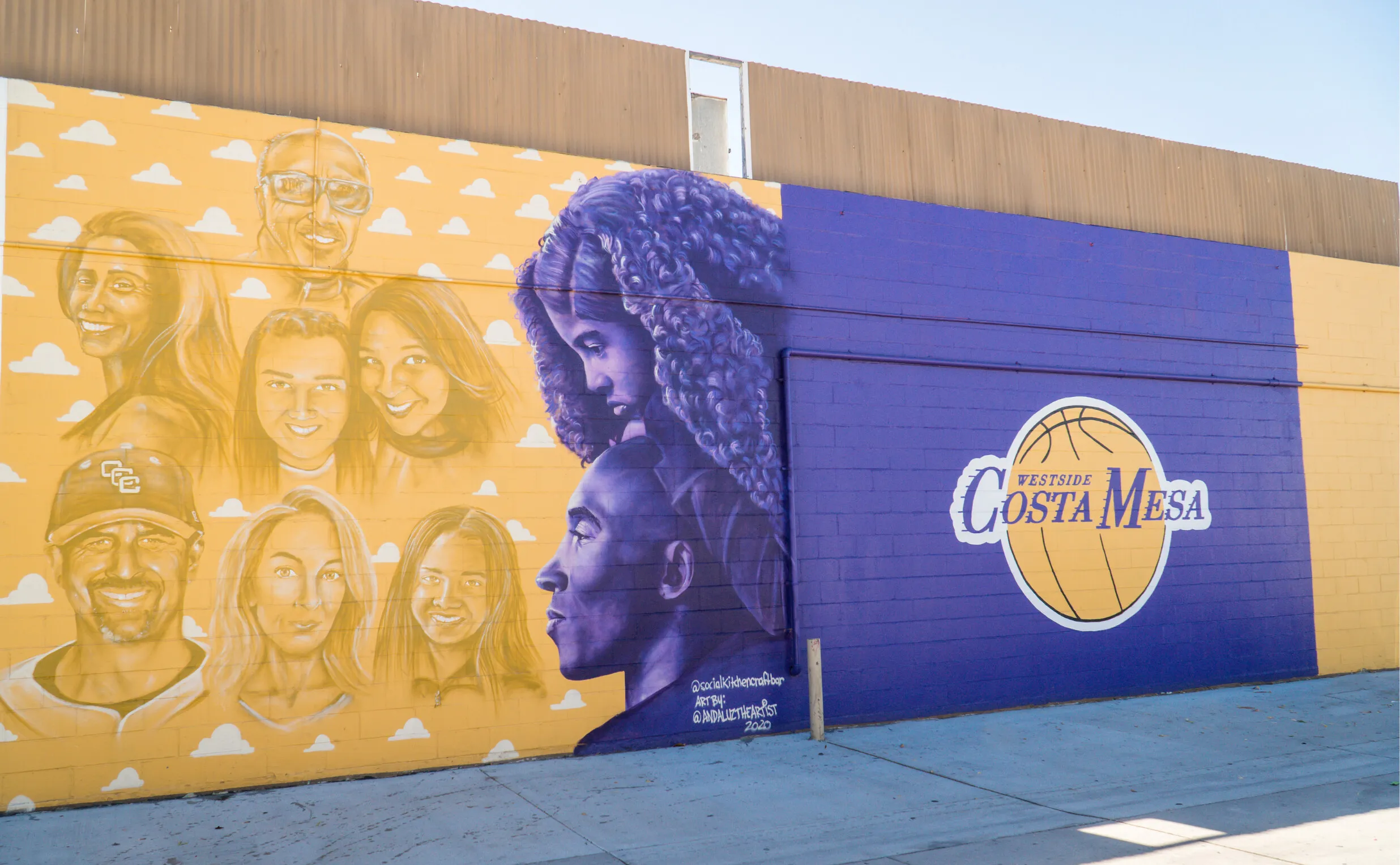 A mural on a wall features yellow and purple tones. On the left, there are realistic portraits of diverse people, while on the right, a large basketball displays Costa Mesa—perfect for any costa mesa travel blog seeking local art.