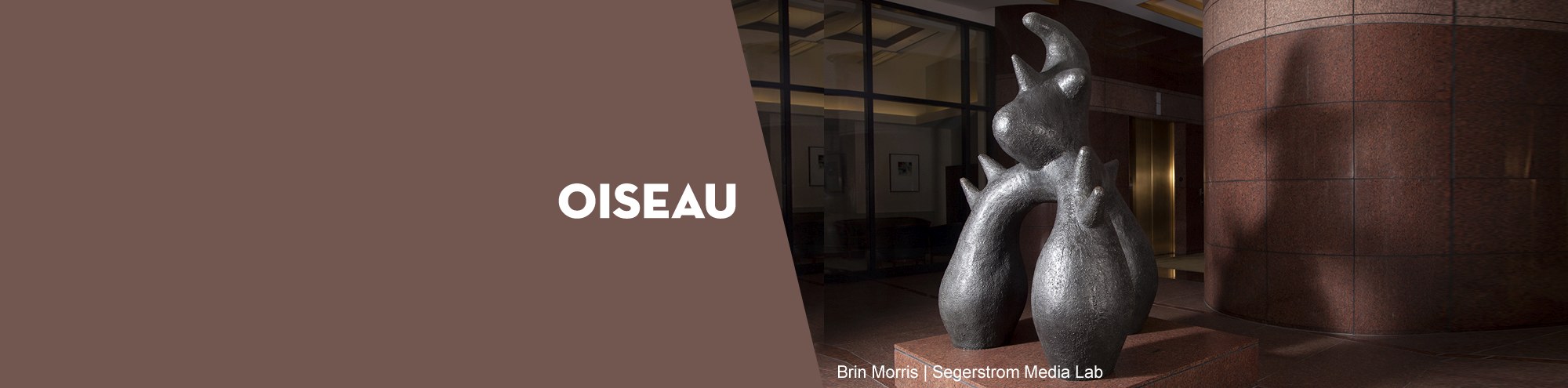 A dark metallic abstract oiseau sculpture stands in a building lobby beside a large red-brown column in Costa Mesa, with OISEAU and photo credit text displayed on a brown background.