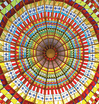 Colorful stained glass dome ceiling viewed from below, featuring geometric patterns in red, yellow, blue, and green radiating outward from a central circular point—a striking sight along the Costa Mesa Art Walk.