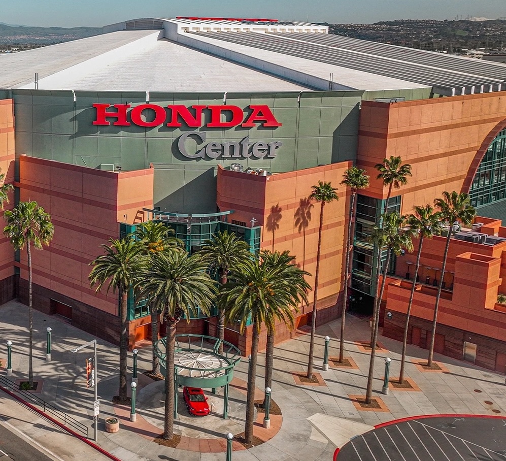 Aerial view of the Honda Center, a large sports and entertainment arena with palm trees at the entrance in Anaheim, California—an exciting stop for day trips from Costa Mesa.